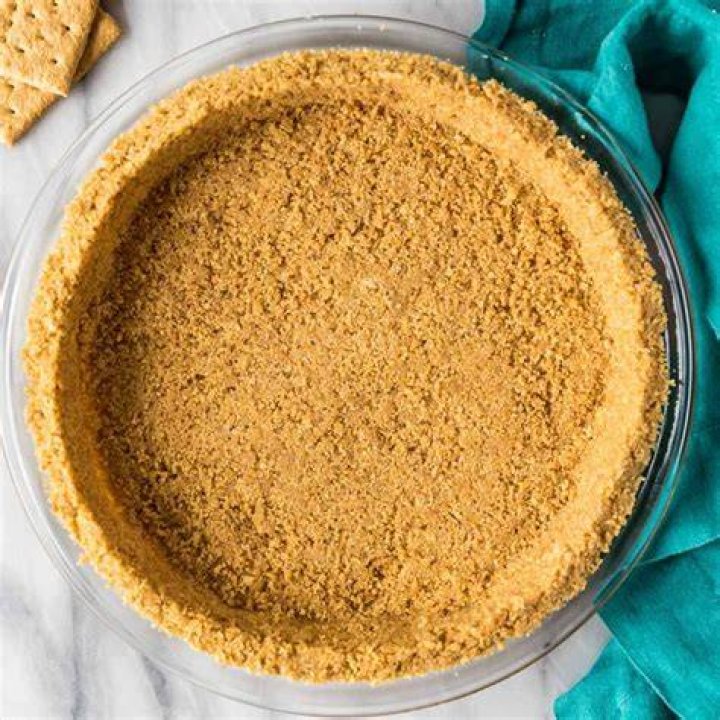 Graham cracker crust in a glass bowl and in a muffin pan.